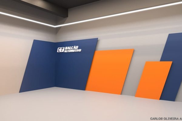 Uma parede interna moderna com painéis angulares em azul e laranja e o logotipo CT BALCÃO AUTOMOTIVO em branco em um painel azul. Design minimalista com piso cinza e iluminação de LED branca no teto.